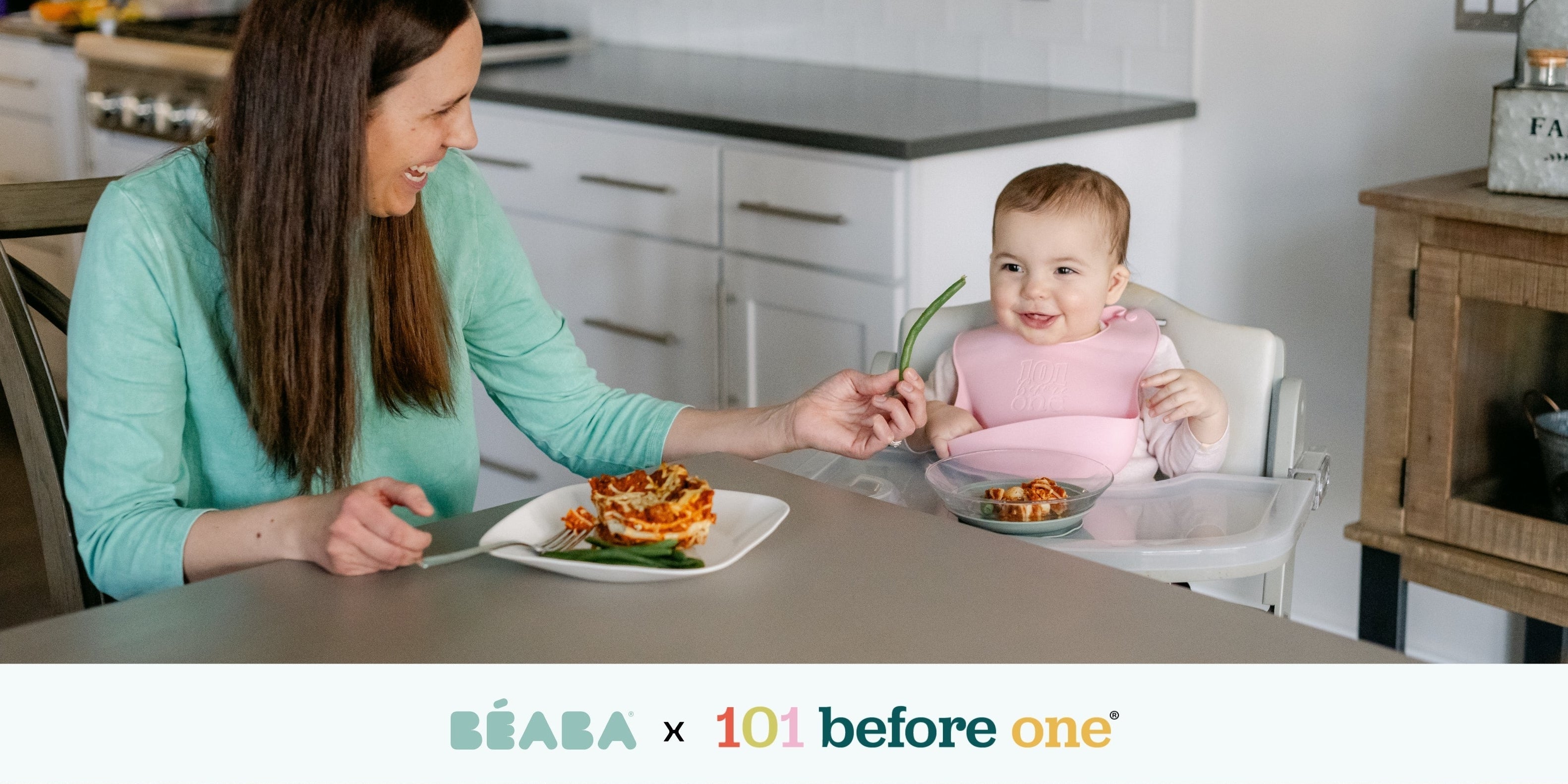 Woman and baby in a high chair eating together at a kitchen table, with 'Béaba' and '101 before one' branding.